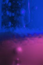 Abstract background composed of blue and purple gel with some bubbles behind glass