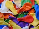 Colorful background texture of deflated party balloons in the colors of the rainbow lying in a random pile, full frame view