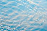 Full frame of white net with center out of focus over blue water color background with copy space