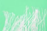 Extreme close up of white plastic fibers against a sea green background