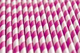 Background pattern of colorful pink and white spiral paper drinking straws viewed in a pile at an oblique angle, full frame