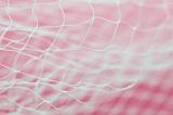 Thin mesh netting with out of focus elements over pink background with copy space