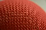 Cropped macro close up view on tightly knit orange fabric over sphere or ball as abstract texture with copy space