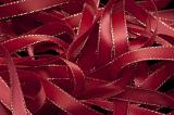 Cropped close up on pile of dark red gift ribbons with gold trim as full frame background with copy space