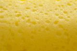 Abstract background composed of close up of one yellow porous sponge with many dark pockmarks
