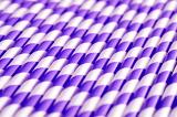 Selective focus view on row of spiral pattern purple and white straws close together for full frame background