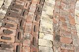 Curving brick paving with decorative pattern of different shapes and colors of brick viewed from above in a full frame background