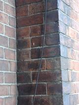 Detail of brick chimney or wall with coaxial line hanging from top to bottom of frame