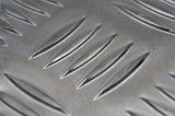 Detailed close up view on smooth checker plate metal surface with five shapes in center