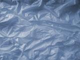 Background texture of crumpled creased blue grey plastic sheeting in a full frame close up view
