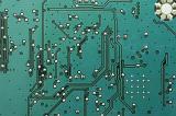 Extreme close up background of circuit board colored green and with various soldered wires