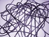 A tangle of thin wires over a white background with purple toning viewed from above forming an abstract pattern and texture