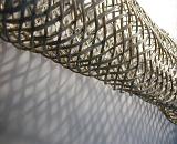 Unique background of security mesh wire fence rolled and casting a shadow on nearby wall