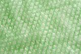 Extreme close up background pattern of green plastic bubble wrap unraveled for full frame with copy space
