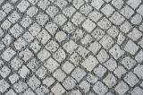 Old worn small square cobblestones in an irregular repeat pattern viewed directly from above in a full frame view