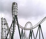 Amusement park roller coaster ride against cloudy sky showing the track doing loop the loops with sharp descents