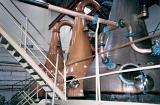 Large copper stills in a commercial distillery producing alcohol in a close up view of the equipment and infrastructure