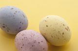 Speckled Candy Easter Eggs in pastel shades of pink, blue and yellow on a yellow background.