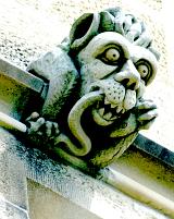 grotesque stone sculpture carved on the side of an old building