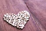 Heart shape composed of little wooden hearts, over lacquered wooden table surface with copy space. Love Valentine concept