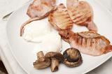 Cooked breakfast of bacon, fried eggs and mushroom served on a plate for a nutritional start to the day
