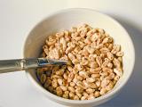 High angle view of commercial puffed wheat breakfast cereal in a white ceramic bowl with a spoon
