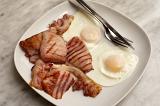 English breakfast with succulent rashers of grilled bacon and two fried eggs served on a plate