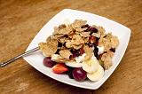 Bowl of muesli with fresh and dried fruit and nuts for a healthy breakfast on a wooden table top