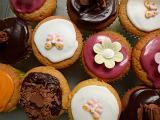 Decorated freshly baked cupcakes viewed from above with their colorful icing and decorative flowers and butterflies ready for a party or celebration