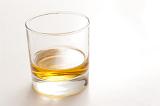 Whiskey or scotch in a glass tumbler served neat without ice on a white background with copyspace