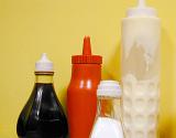 Condiments in a takeaway chip shop in plastic containers including ketchup, mayonnaise , brown vinegar and salt