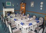 Stylish modern white dining suite with a long table and chairs set with twelve formal place settings in blue decor