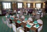 Hotel dining room with long tables set for lunch or dinner with formal place settings