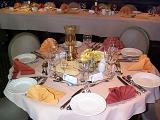 Elegant dining table at a catered event set with six place settings with luxury linen, silverware , name cards and white plates