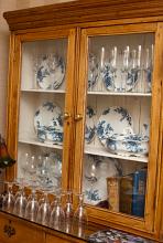 Plates from a blue and white dinner service displayed in an old rustic glass fronted wooden dresser