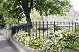 Wrought iron garden fence in a city with spikes in a corner view of the property with lush greenery and leafy green trees