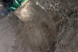 Digging garden soil with a spade with a close up view of earth trickling off the blade as it is raised