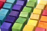 Colorful arrangement of wooden building blocks or cubes in neat rows ordered by color in a full frame background