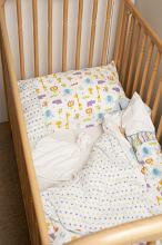 Empty wooden cot or crib for a young child with decorative linen viewed high angle