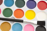 New water color paints in an open box with an unused paint brush in a close up overhead view