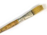 Old used wooden oil color paintbrush with bristles lying diagonally across the frame on white with copy space