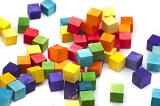 Bright multicolored wooden toy blocks in the colors of the rainbow scattered in a heap on a white background