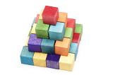 Stacked colorful wooden kids toy bricks in the colors of the rainbow arranged in a pyramid on a white background, high angle view