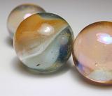 Close Up of Three Glass Marbles in Different Sizes on White Studio Background with Foreground Copy Space