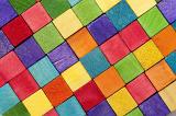 Vibrant background pattern of wooden toy blocks in the colors of the rainbow arranged in rows to form a diamond pattern in a full frame view