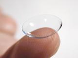 Man holding a plastic disposable contact lens on his finger for correcting visual acuity in a healthcare, optical and medical concept