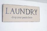 Humorous sign on a white exterior Laundry wall - Drop Your Pants Here