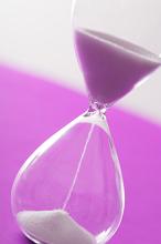 Sand running through an hourglass measuring the passing time counting down to a deadline over a bright pink background