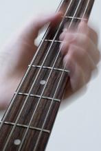 a hand playing a bass guitar
