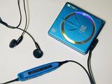 Sony Mini Disk personal music player of blue color with black earbuds and on wire controls, from above close-up on white background